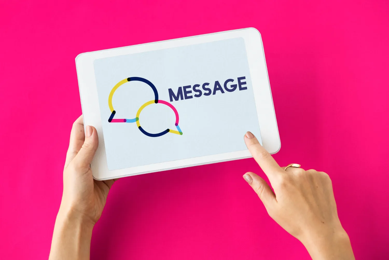 Hands holding a tablet displaying a message icon with two speech bubbles and the word 'MESSAGE' on a vibrant pink background.