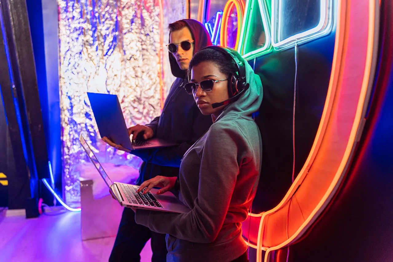 Hackers with laptops under neon lights in cyberpunk style.