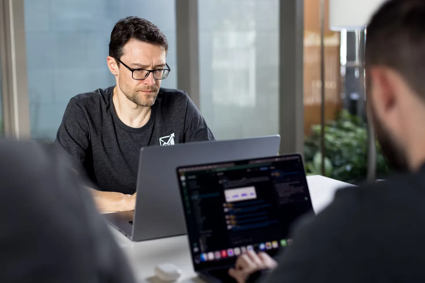 Software developers focused on coding on their laptops in a collaborative work environment.