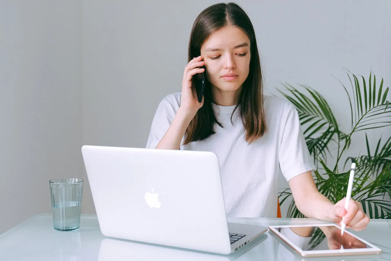 Professional woman on call using Mac simultaneously.