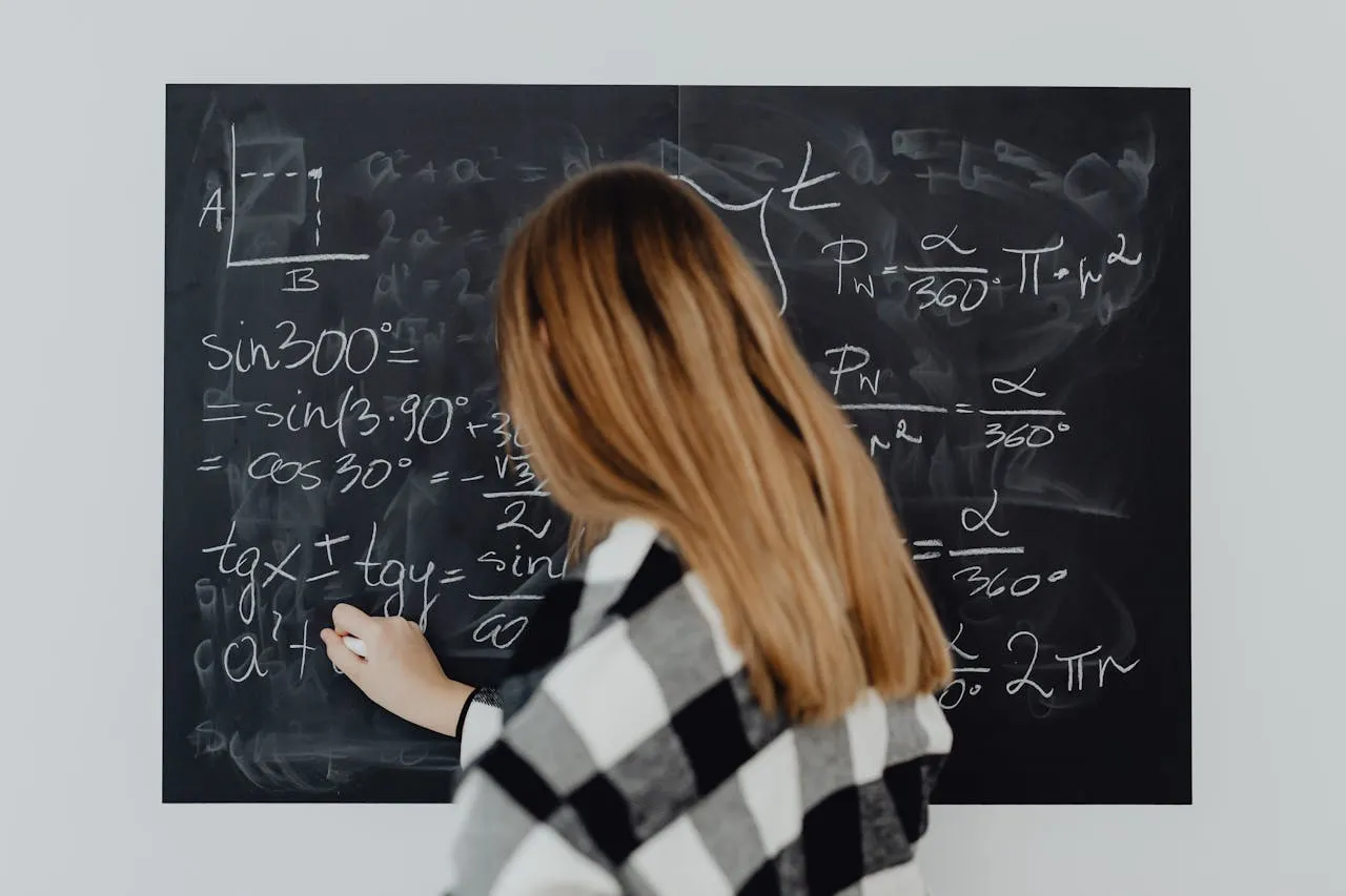 Student writing trigonometry formulas on chalkboard with geometric diagram.