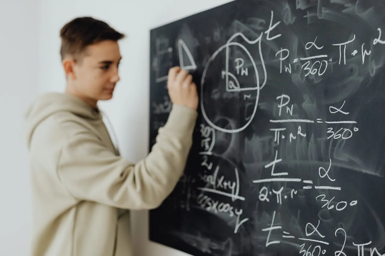 Student writing sector area formulas (α/360°×πr²) on chalkboard.
