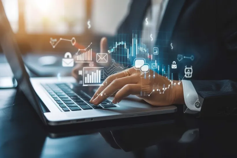 Professional using laptop with digital financial graphs and charts.