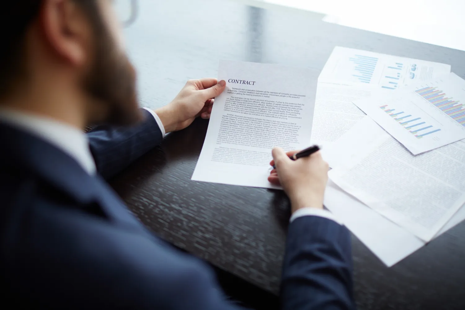 Businessman reviewing and signing a contract on a desk.