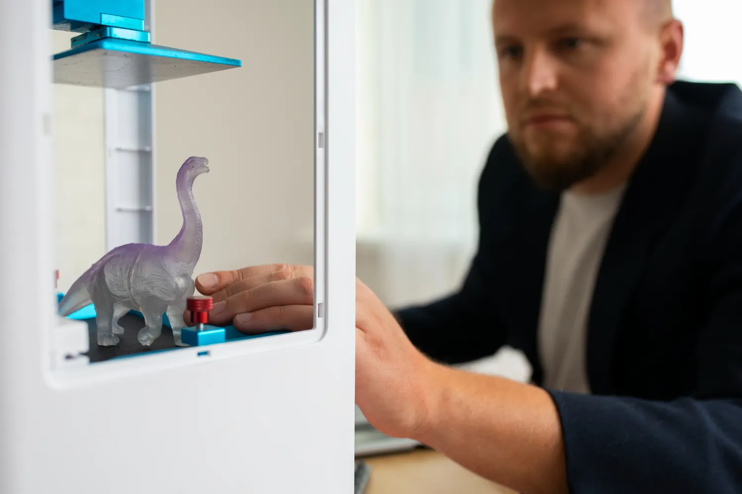 Man using a 3D printer to create dinosaur figurine