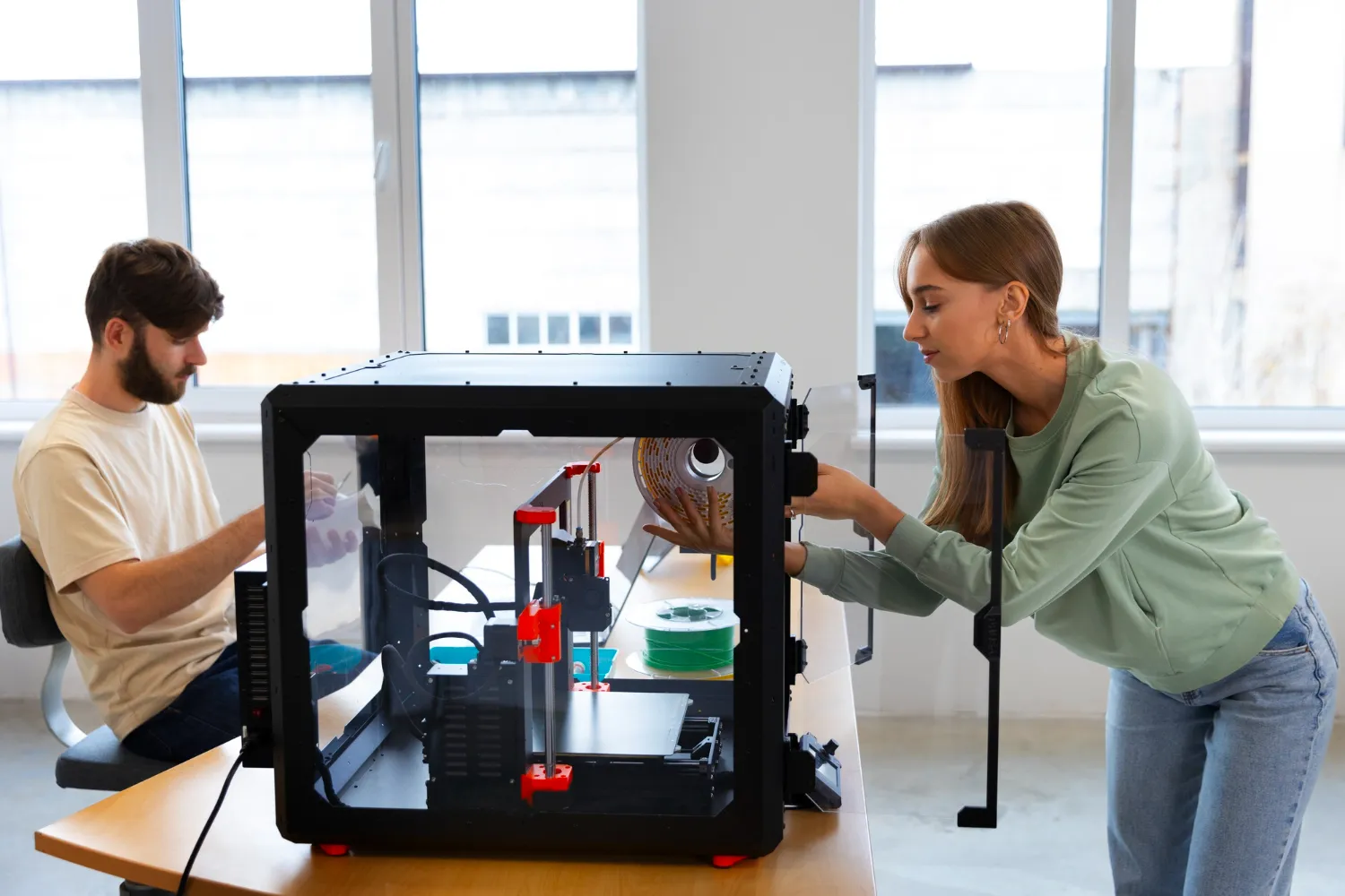 Two students working with a 3D printer in a classroom