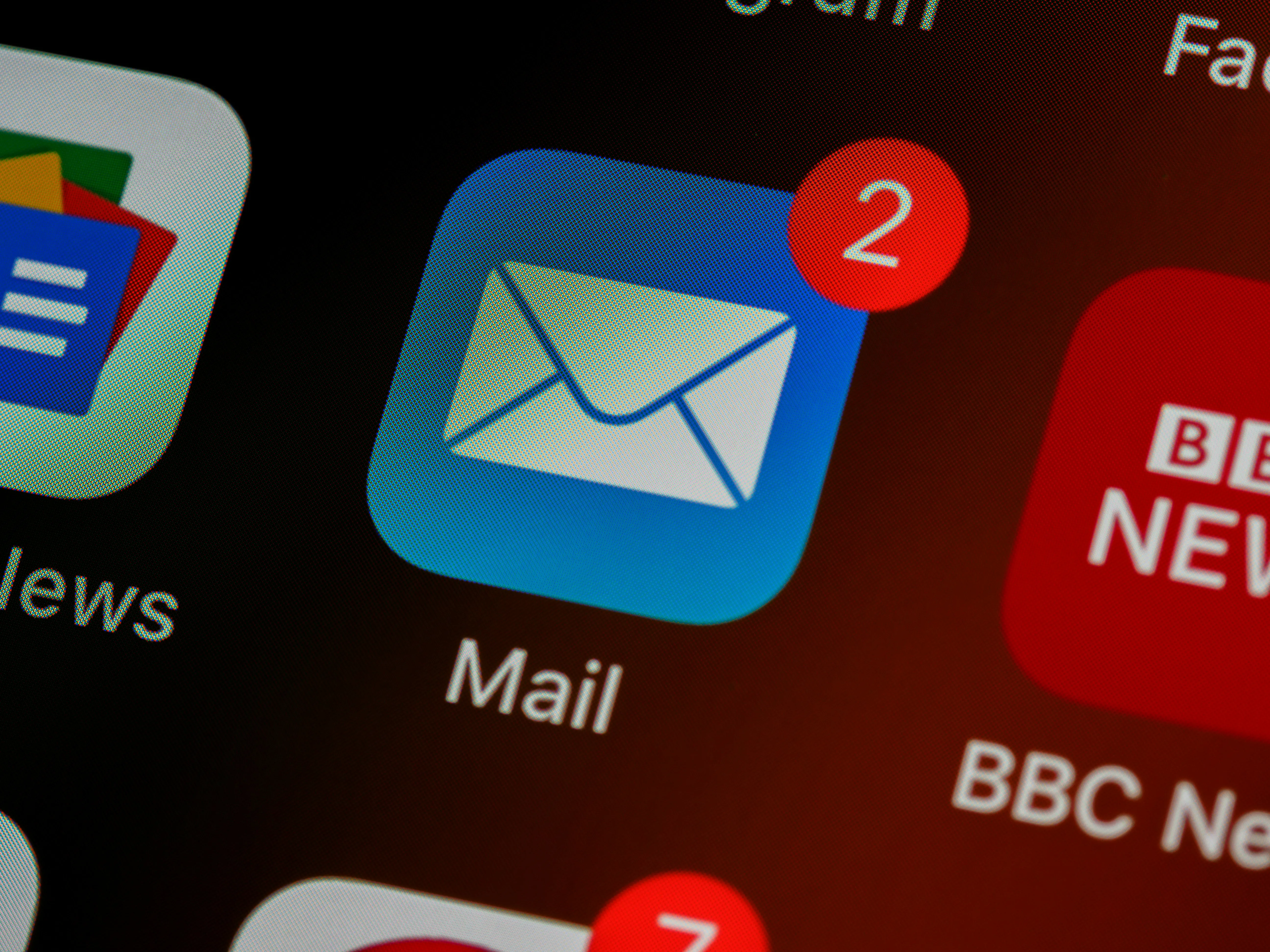 Close-up of a mobile screen showing an email app icon with two unread notifications, alongside other app icons.