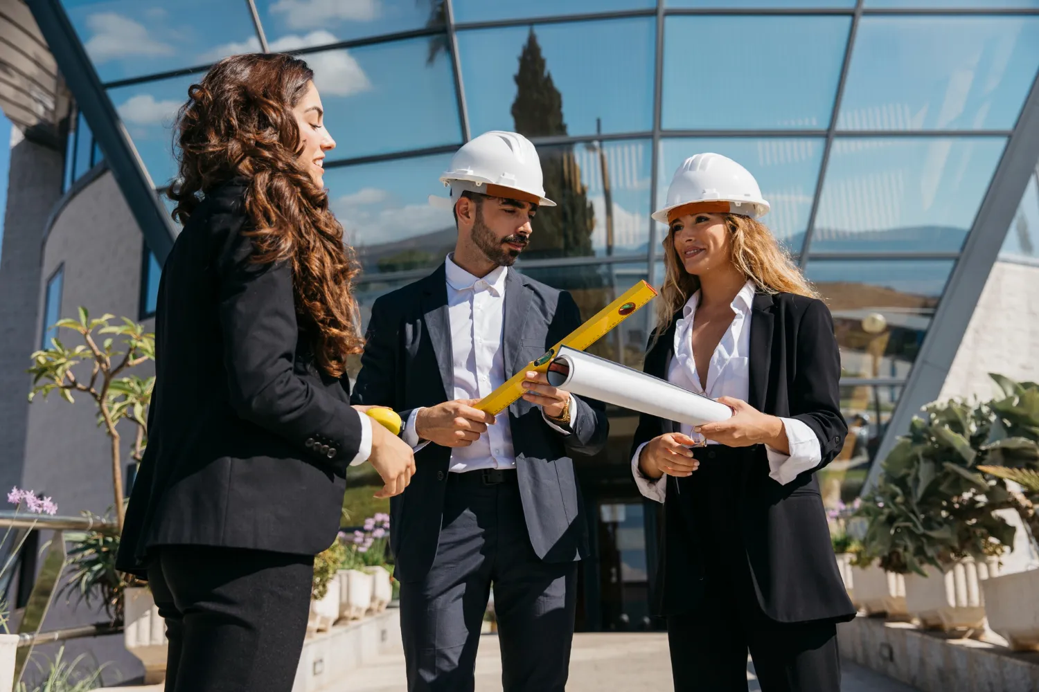 Architects in hard hats discuss blueprints, showcasing teamwork in construction.