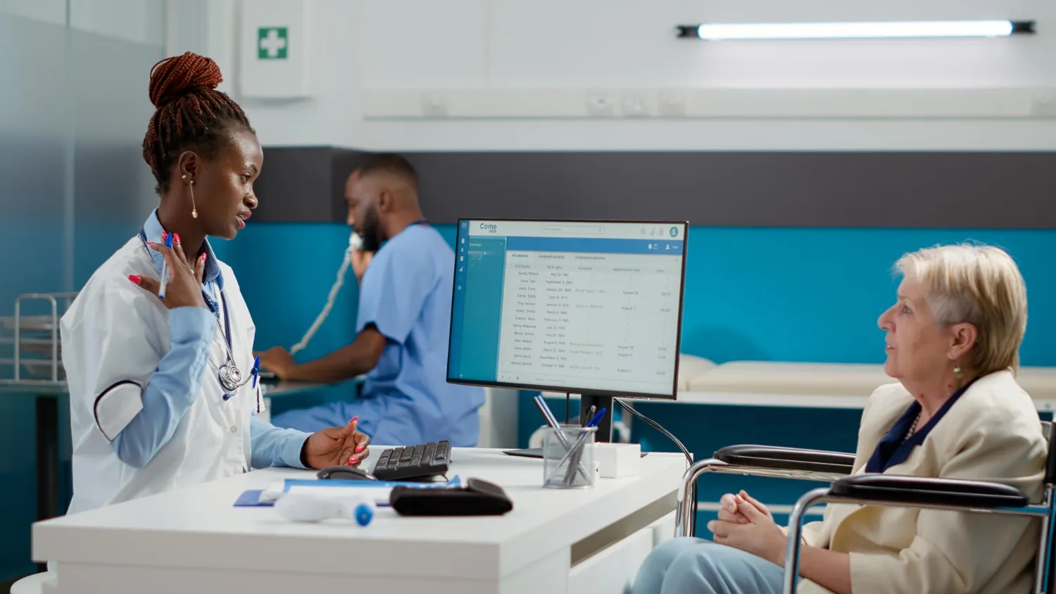 Doctor consulting a patient with medical records displayed on screen.