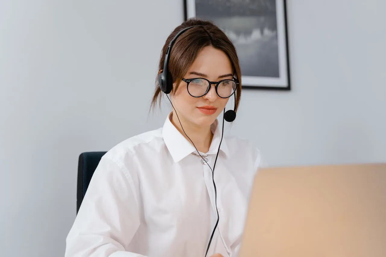 Woman with headset working on a laptop in a workspace.