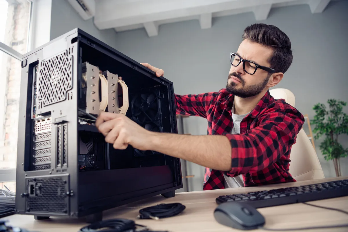 Computer technician assembling a desktop PC, focusing on hardware installation and maintenance in a modern workspace.