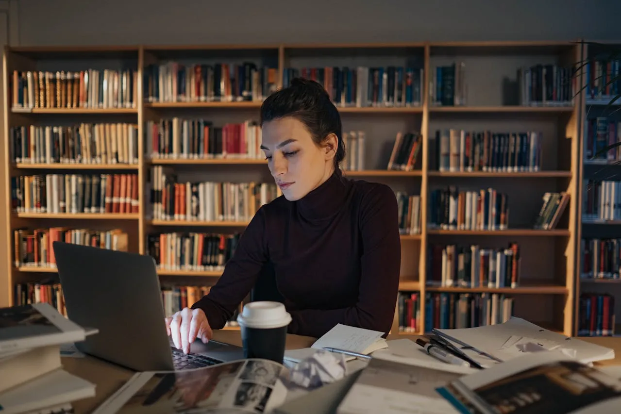 Student studying on a laptop in a quiet library.