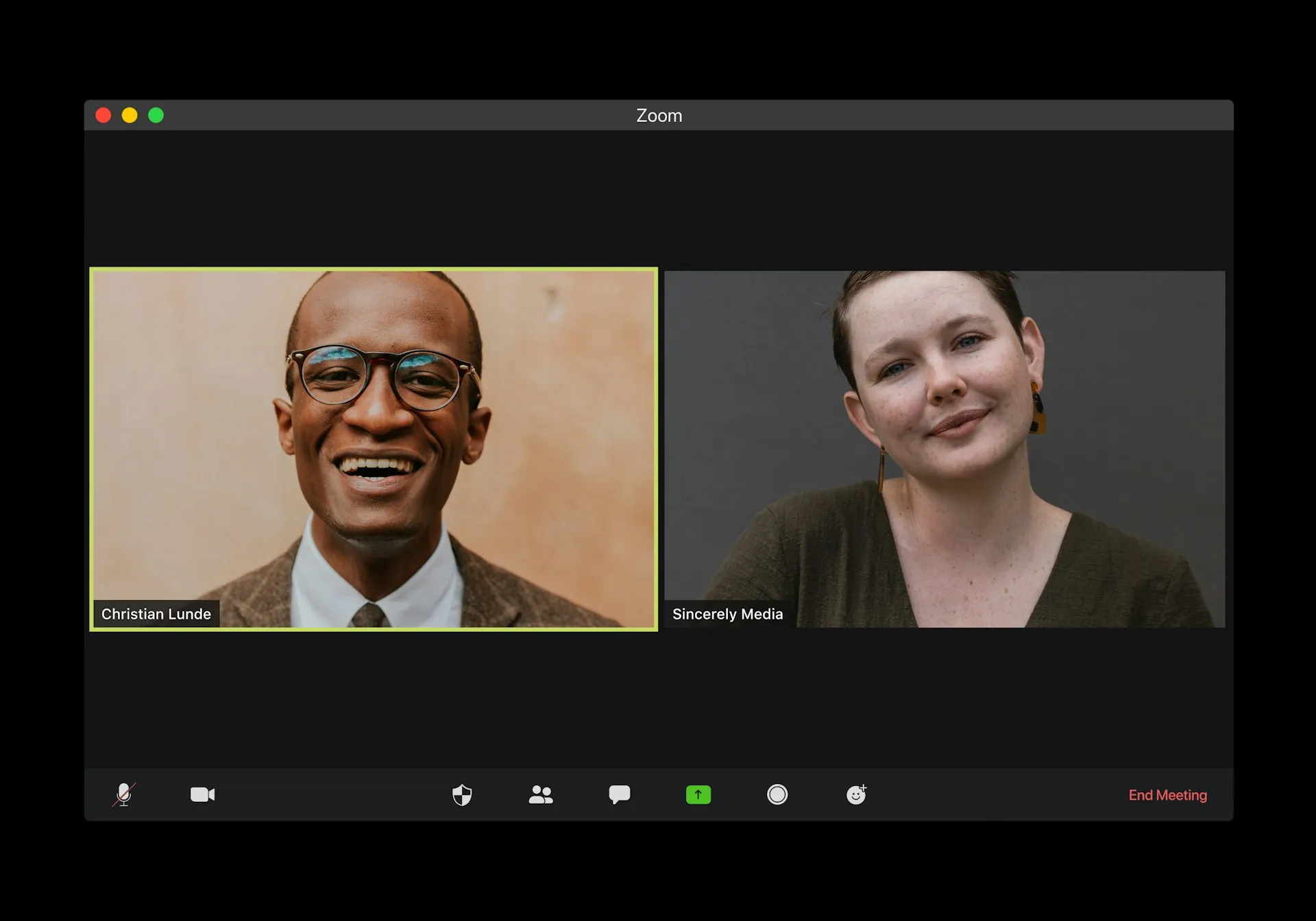 Zoom video call interface showing two participants: smiling man with glasses and woman in green sweater, with meeting controls visible