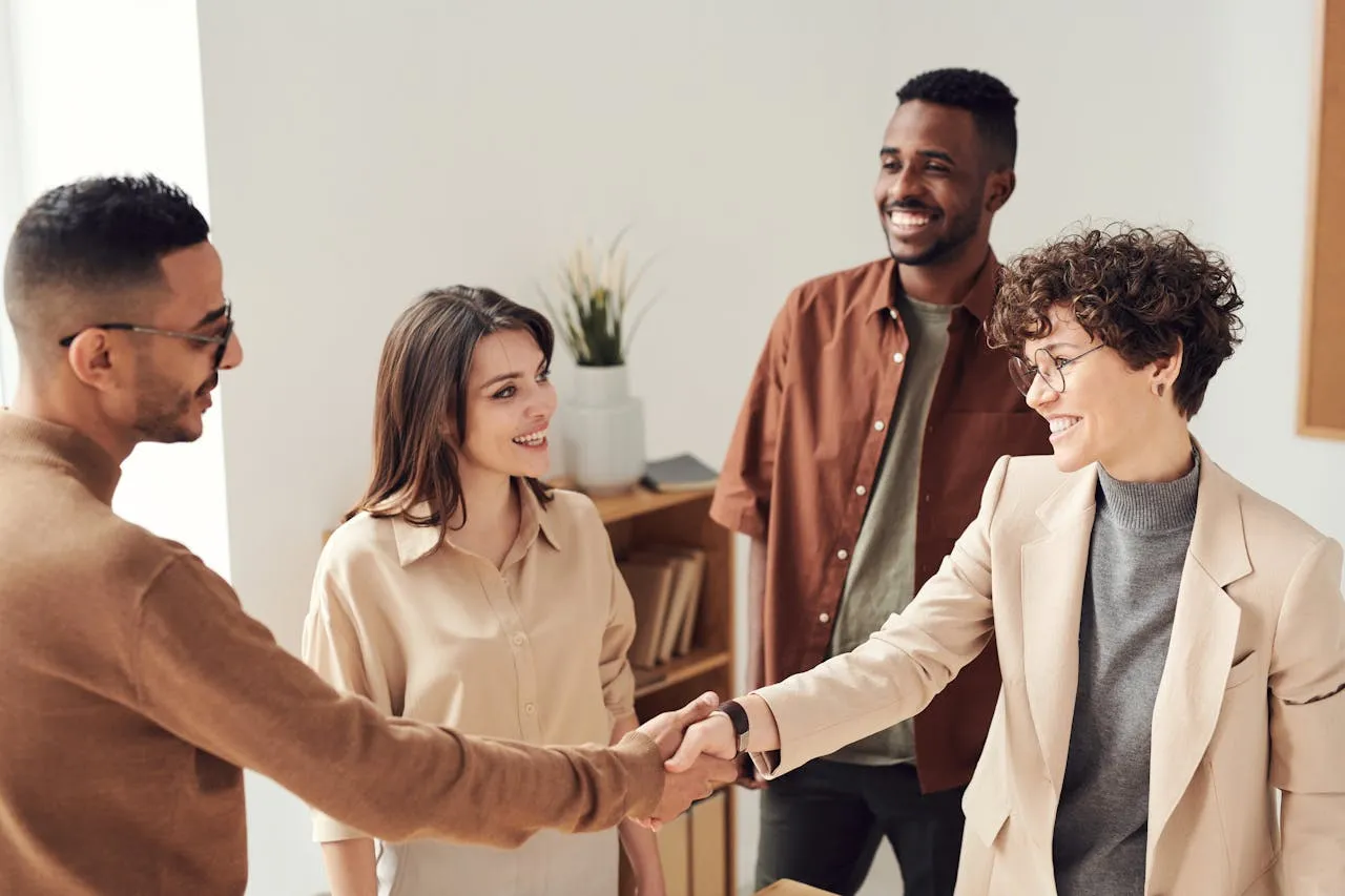 Diverse team shaking hands in modern earth-toned office meeting