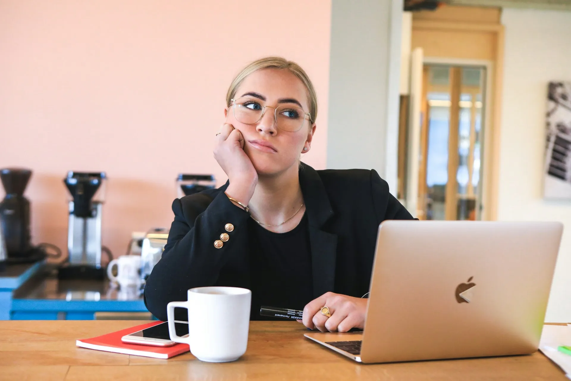Professional woman working on MacBook in modern café workspace.