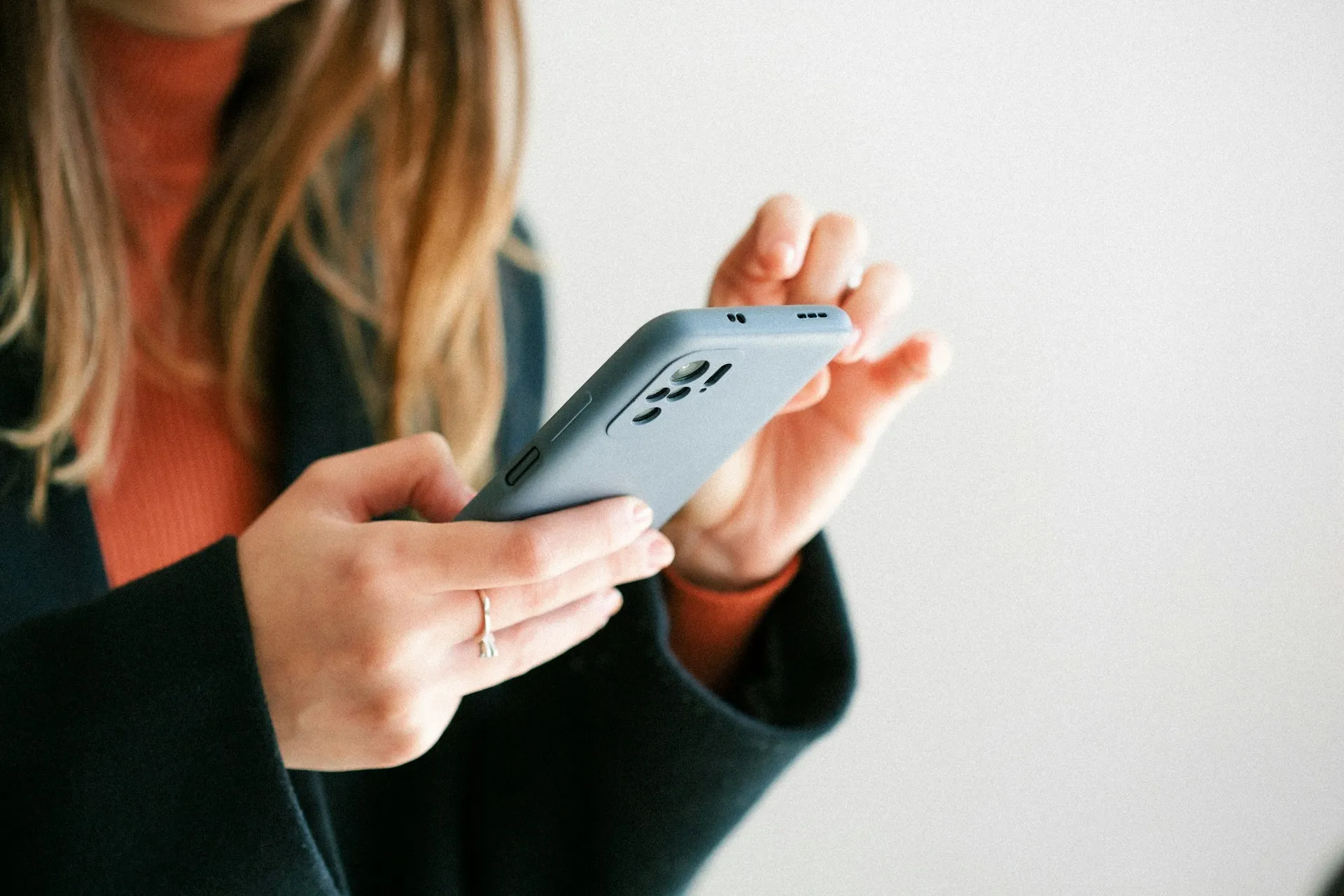 Woman holding and using a smartphone indoors, focused on the device.