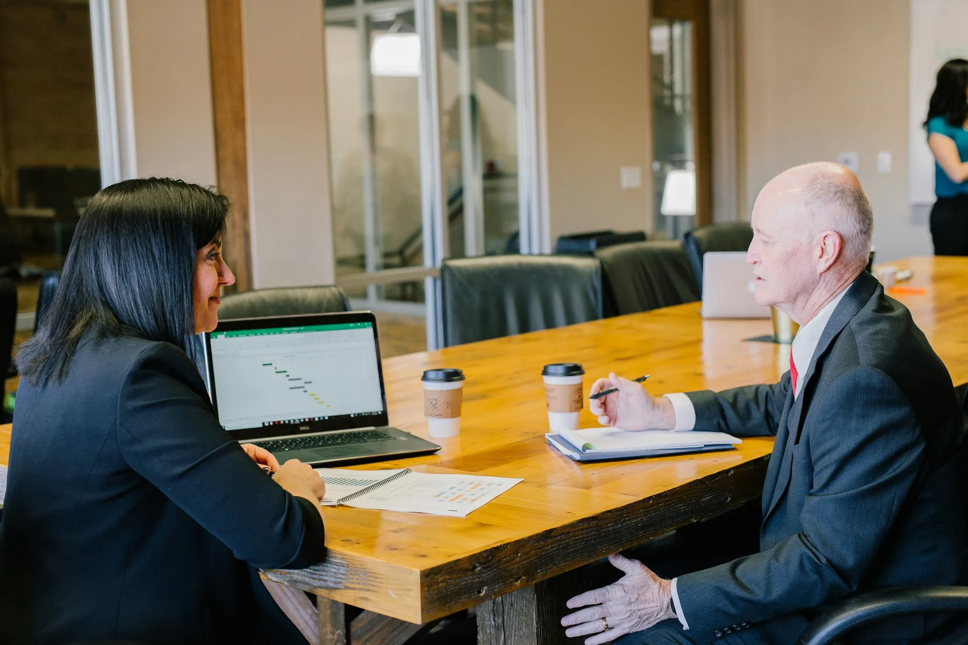 Business team discussing project with laptop, Gantt chart, and coffee.