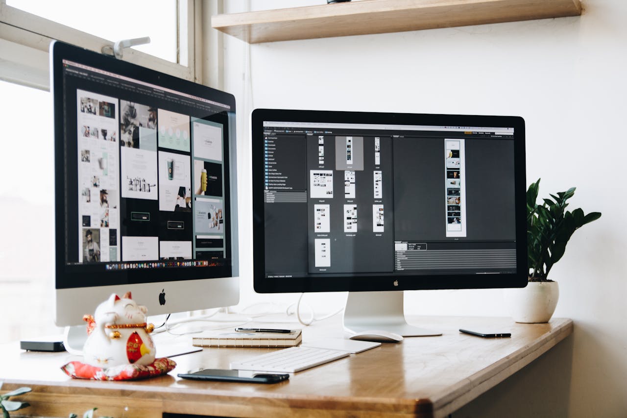 Two monitors showing design project in a creative workspace.