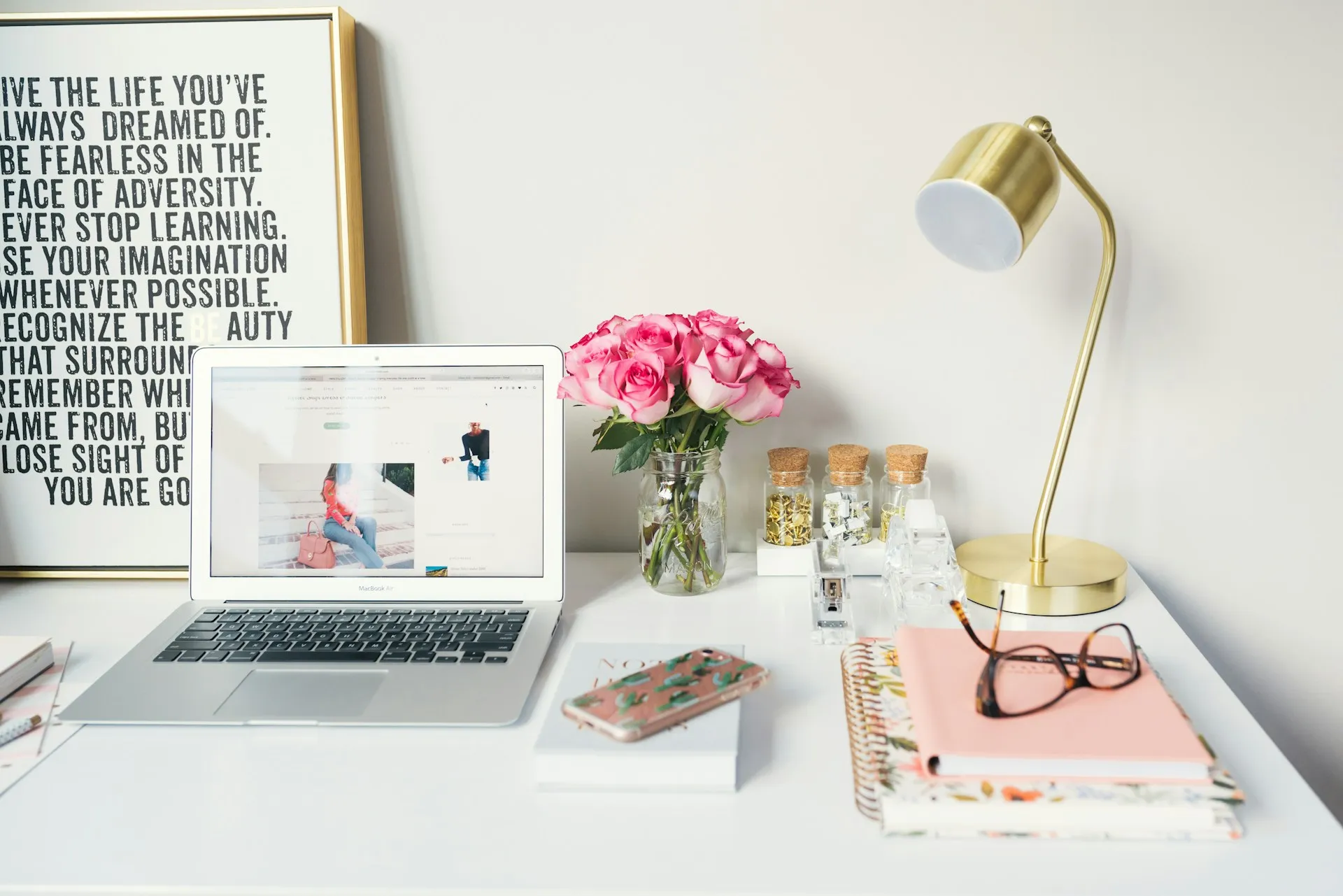 Inspiring home office desk with laptop, flowers, and motivational decor.