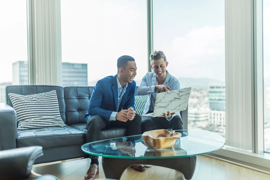 Business meeting on leather sofa with laptop and cityscape.