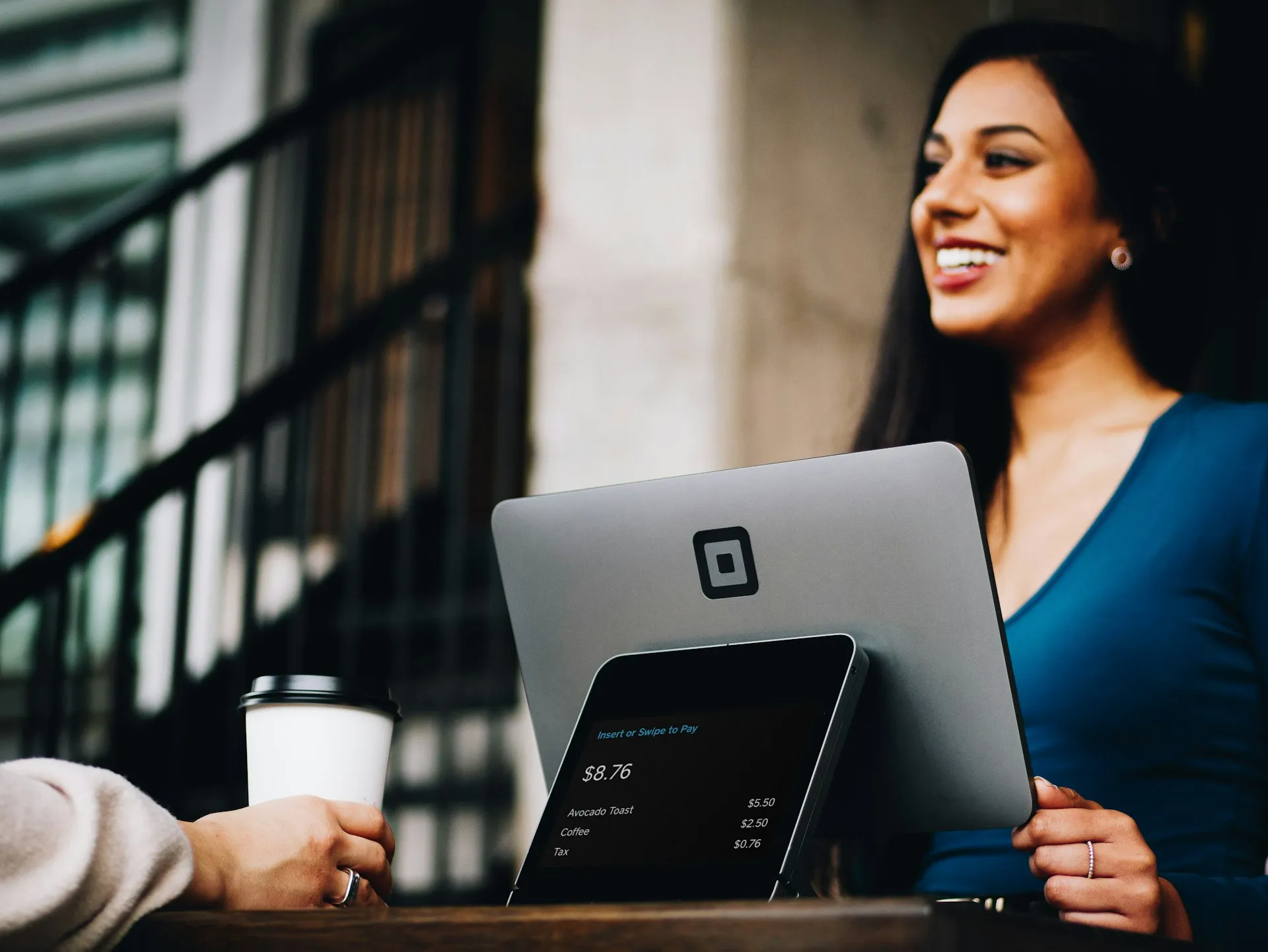 Person making a payment at a coffee shop with a Square payment terminal.