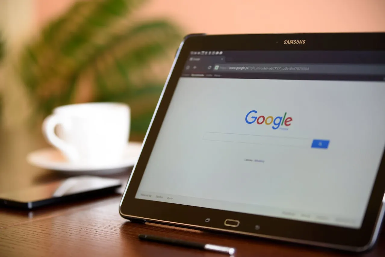 Samsung tablet on wooden desk showing Google search page with stylus.
